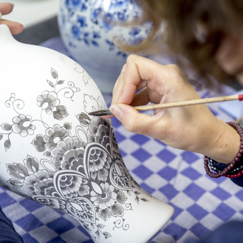 Delfts blauw schilder aan het werk bezig met het beschilderen van een vaas Heinen Delfts Blauw