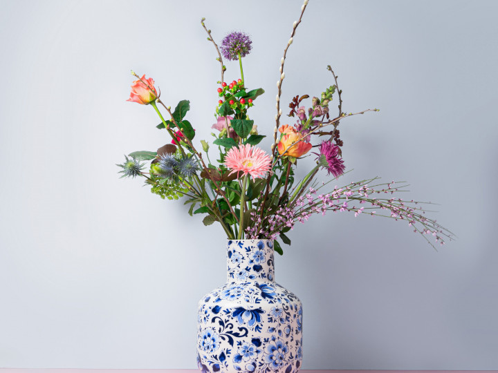 Kleurrijke bos bloemen in een grote witte bolvaas met Delfts blauwe bloemen decoratie.